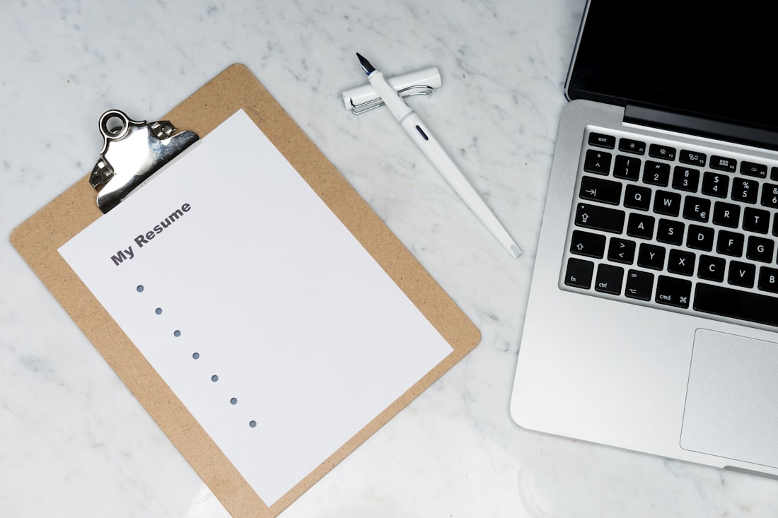 A printed resume on a clipboard beside a laptop and pen, ready for ATS-friendly formatting